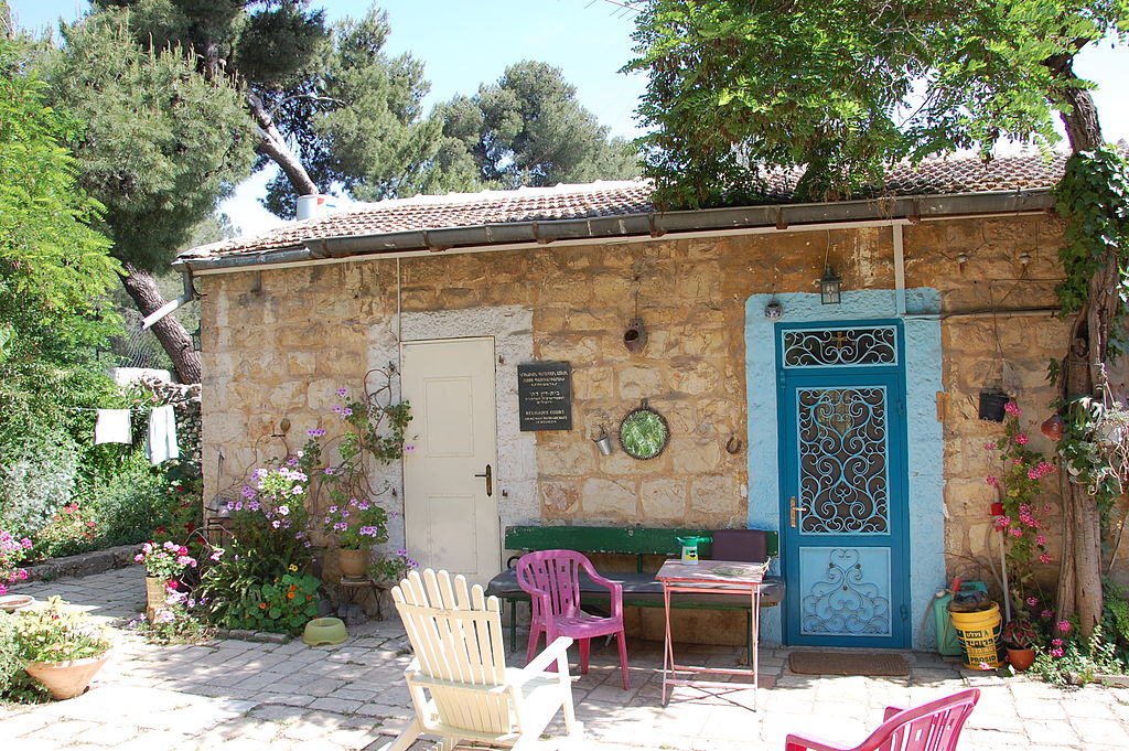 a small brown house with chairs in front