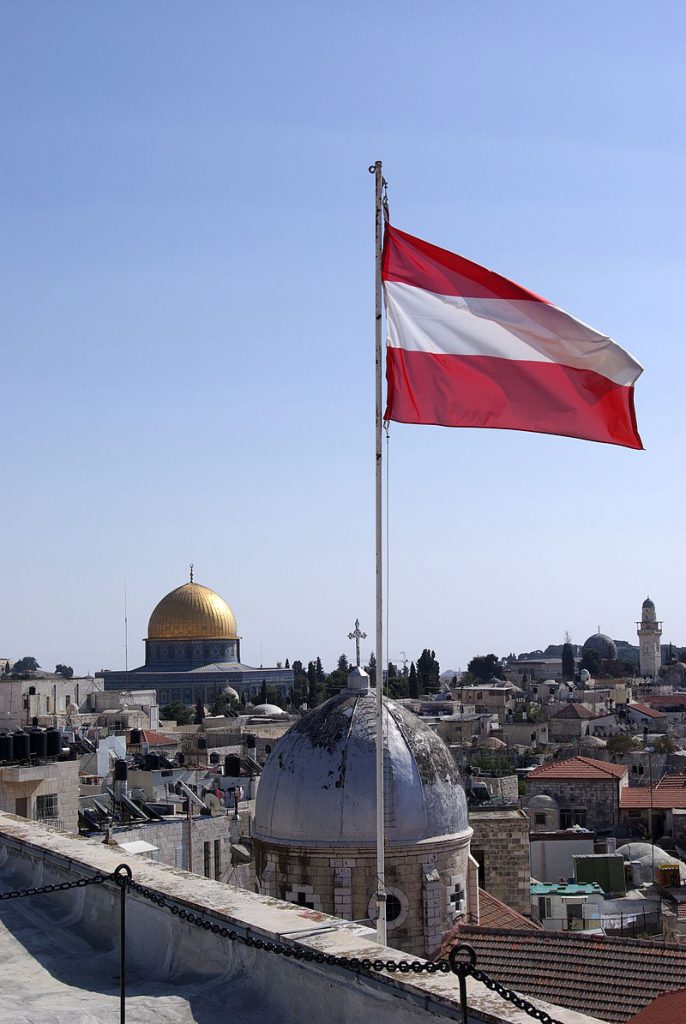A red-and-white striped flag overlooking a city