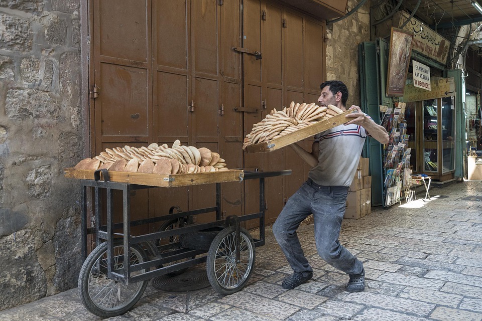 a man carrying a crate of box of bread, with the crate of bread in front of him