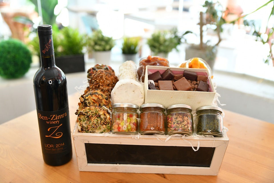 a bottle of wine beside a crate of bottled food and cheese