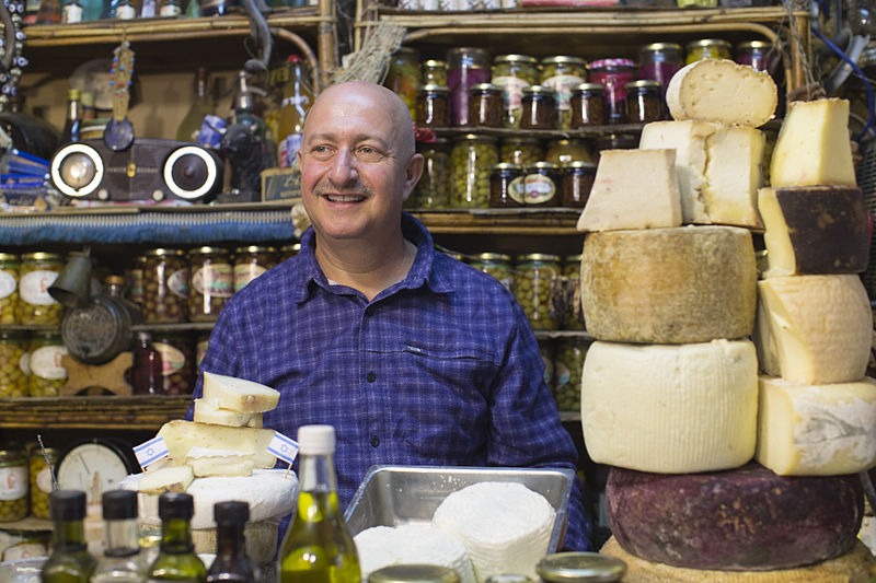 a man selling cheese and olives