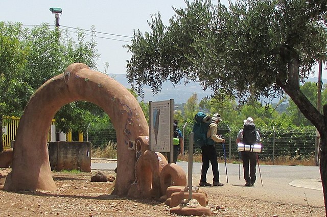 two men hiking beside an arched sculpture, in kibbutz Dan starting point