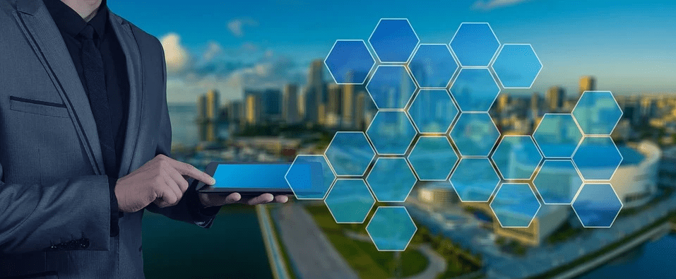 Man in a business suit holding a tablet, with background a business district and superimposed with hexagon images