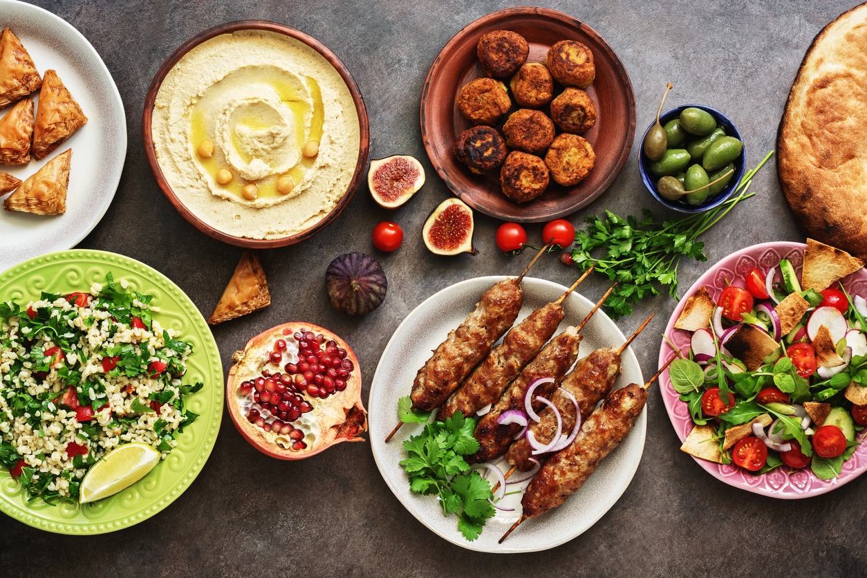 Arabic and Middle Eastern dinner table. Hummus, tabbouleh salad, Fattoush salad, pita, meat kebab, falafel, baklava, pomegranate. Set of Arabian dishes.Top view, flat lay